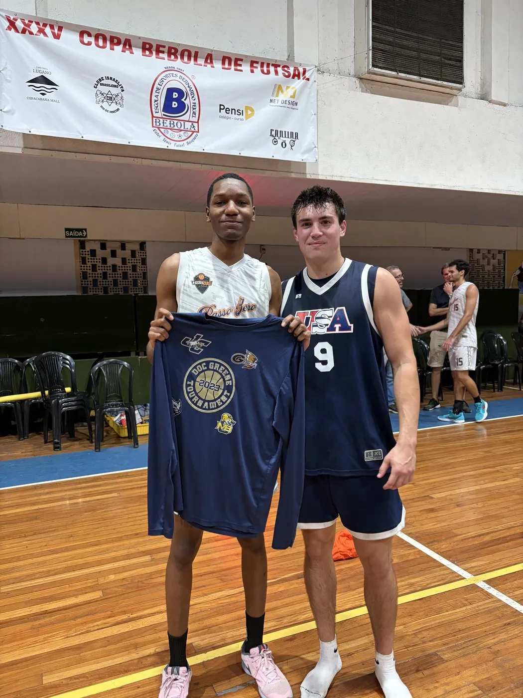 A USA Sports athlete and a Brazilian player trade jerseys at the Copa Bebola de Futsal